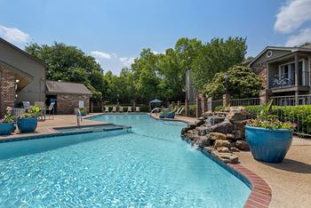 A swimming pool surrounded by a stone wall and potted plants